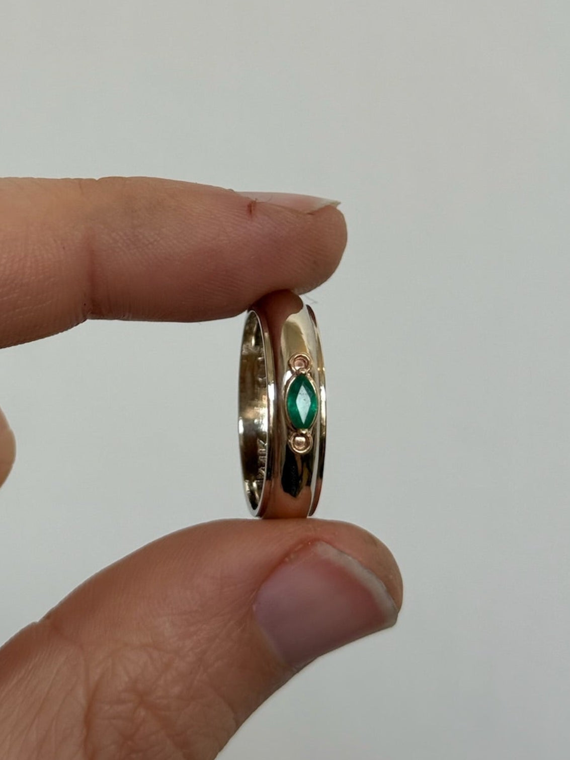 Gold ring with a green gemstone held 
