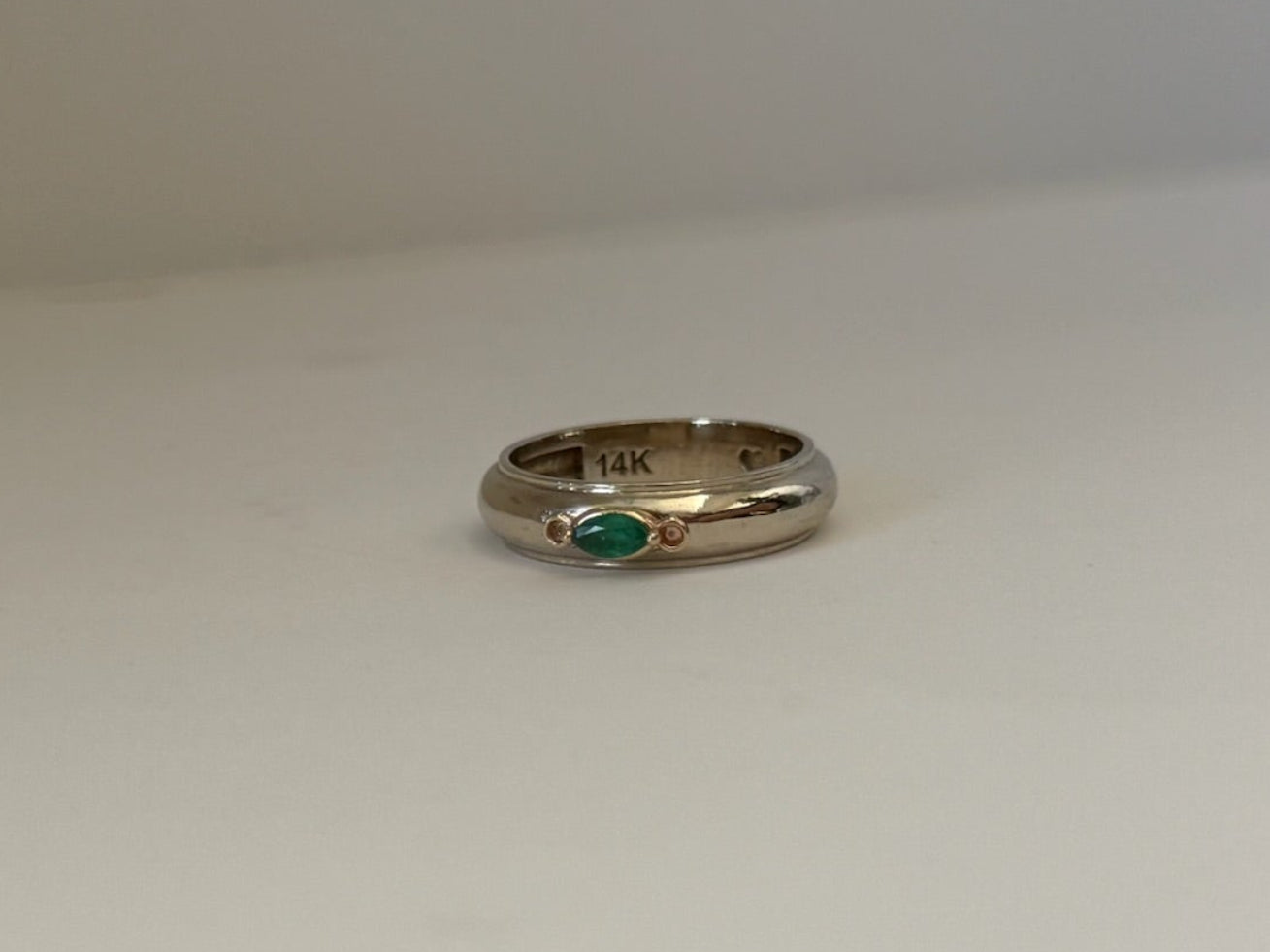 Gold ring with a green gemstone on a white surface
