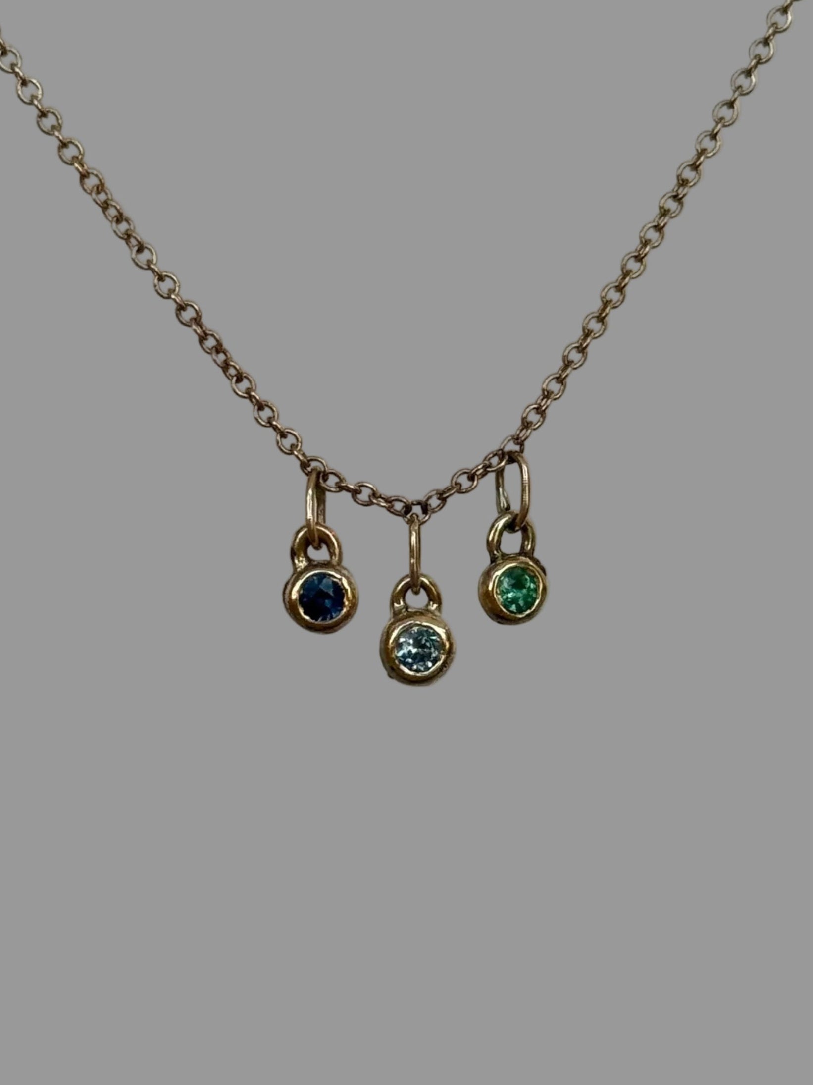 Necklace with three small pendant charms on a plain background