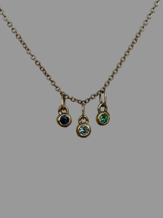 Necklace with three small pendant charms on a plain background