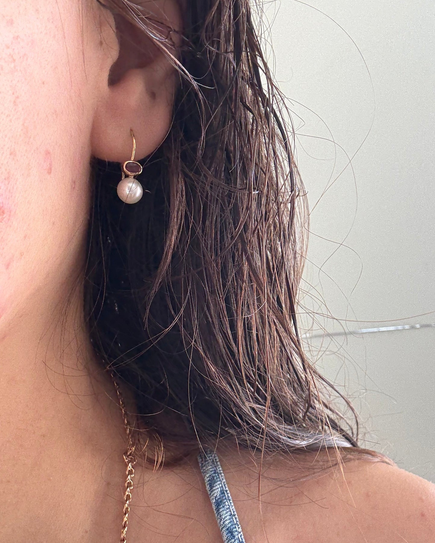 Close-up of a pearl earring worn by a person with a neutral background